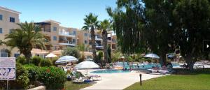 una piscina con gente en un complejo con palmeras en Modern and stylish 1 bedroom apartment in King's Palace en Paphos