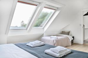 two beds in a white room with two windows at Queen's Cave By Staysville in Stavanger
