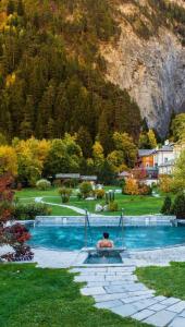 a man sitting in a swimming pool with a mountain at La Maisonnette de Stefano in Pré-Saint-Didier