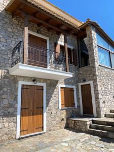 ein Steinhaus mit 3 Türen und einem Balkon in der Unterkunft Tripio Lithari - Arachova Vacation Home in Arachova