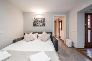 een slaapkamer met een groot bed met witte lakens en kussens bij Modena AL Mulèin - 2 passi dal centro con parcheggio in Modena