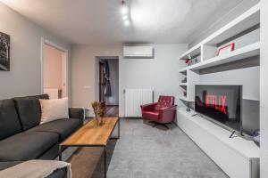 een woonkamer met een bank en een tv bij Modena AL Mulèin - 2 passi dal centro con parcheggio in Modena