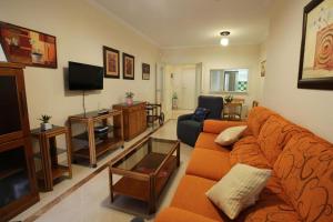 - un salon avec un canapé orange et une télévision dans l'établissement Apartamento Los Moriscos Golf Playa Granada, à Motril