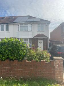 a white house with solar panels on top of a brick wall at Double room in Canvey