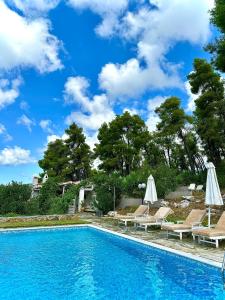 a swimming pool with lounge chairs and umbrellas at Villa Pine Trees by Kardous in Alikias