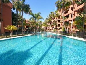 une grande piscine avec des palmiers et un bâtiment dans l'établissement Apartamento Los Moriscos Golf Playa Granada, à Motril