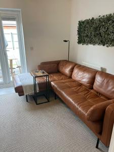 un sofá de cuero marrón en una sala de estar con mesa en Modern 2 Bed house - HS2, NEC & Birmingham Airport en Marston Green