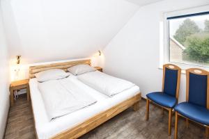 - une chambre avec un lit et deux chaises bleues dans l'établissement Maike, FeWo 15b, à Duhnen