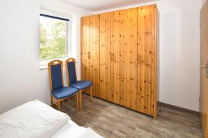 - une chambre avec 2 chaises bleues et un mur en bois dans l'établissement Maike, FeWo 15b, à Duhnen