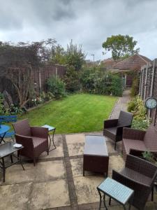 a patio with chairs and tables and a yard at Betty's retreat in Cheshunt