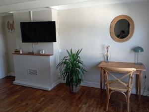 a living room with a table and a television on a wall at LA PETITE BRETONNE in Noyal-Muzillac