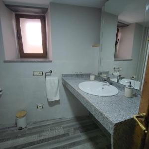 baño con lavabo, espejo y ventana en Habitaciones Pumarada 2, en Cangas del Narcea