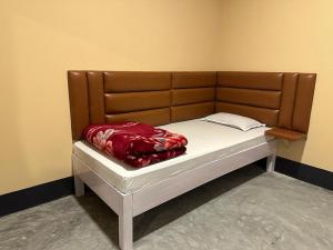 Bett mit einem Kopfteil aus Holz und einer roten Decke darauf in der Unterkunft Camp Buffalo Retreat in Jyoti Gaon