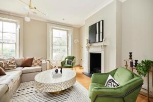 uma sala de estar com um sofá, cadeiras e uma mesa em The Brimmington Park Escape - Lovely 3BDR House with Study Room + Garden em Londres