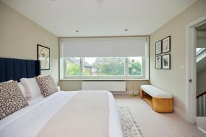 a bedroom with a large white bed and a window at The Brimmington Park Escape - Lovely 3BDR House with Study Room + Garden in London