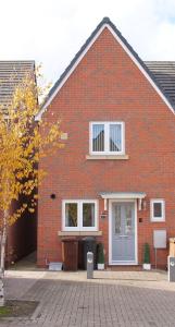 una casa de ladrillo rojo con una puerta gris en Modern 2 Bed house - HS2, NEC & Birmingham Airport, en Marston Green