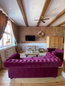 a large purple couch in a living room with a ceiling at Apartments PSD - Anny Łajming 2B in Słupsk