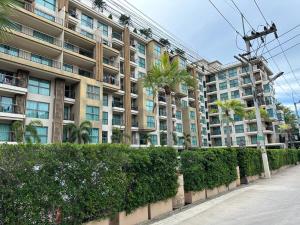 a large apartment building with palm trees and a sidewalk at City Garden Tropicana Condo Naklua in Pattaya North