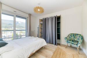 a bedroom with a bed and a chair and a window at Superbe : parking gratuit + fibre wifi + balcon in Grenoble