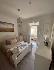 a bedroom with a white bed with a desk and a window at The Beach House in Lowestoft