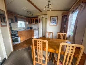 a kitchen and dining room with a wooden table and chairs at Caravan By The Sea At California Cliffs Holiday Park In Norfolk Ref 50014b in Great Yarmouth