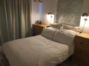 a bedroom with a bed with white sheets and pillows at Cedar Shade Cottage Ensuite Private Annexe with Parking in Sidmouth