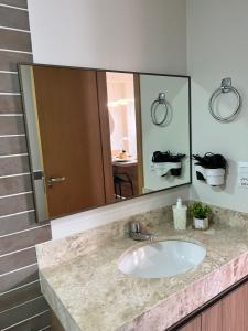 a bathroom with a sink and a large mirror at Flat Super Luxo - Rio Quente - Acesso Ao Rio in Rio Quente