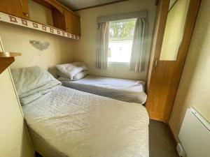 a small room with two beds and a window at Caravan By The Sea At California Cliffs Holiday Park In Norfolk Ref 50014b in Great Yarmouth