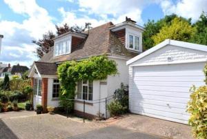 una piccola casa bianca con un garage bianco di Cedar Shade Cottage Ensuite Private Annexe with Parking a Sidmouth