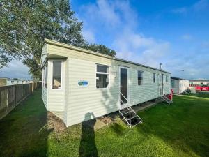 a white tiny house sitting on a lawn at Caravan By The Sea At California Cliffs Holiday Park In Norfolk Ref 50014b in Great Yarmouth