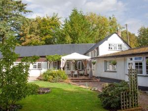 une maison blanche avec un parasol dans la cour dans l'établissement Little Millhayes, à Thorverton