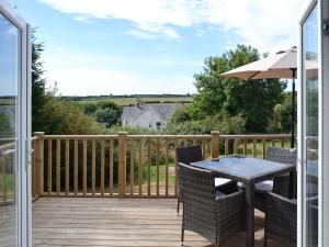 a patio with a table and chairs on a deck at Spring Cottage in Kentisbury