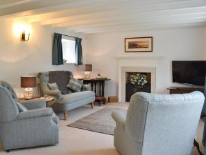 a living room with two chairs and a tv at Sunny Cottage in Bulmer