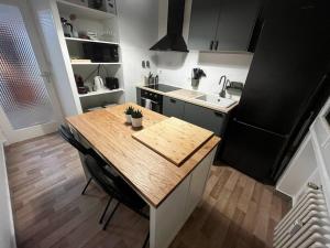 eine Küche mit einem Holztisch und einem Kühlschrank in der Unterkunft 4 personnes - ambiance cosy - proche universités in Grenoble