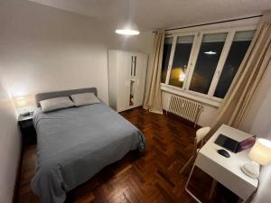 Schlafzimmer mit einem Bett, einem Tisch und einem Fenster in der Unterkunft 4 personnes - ambiance cosy - proche universités in Grenoble