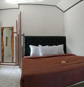um quarto com uma cama com uma cabeceira preta e um espelho em Wikan House em Bebandem