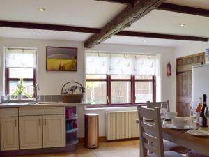 a kitchen with a table and some windows at Heathcote Cottage in Hickling