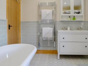 a bathroom with a tub and a white dresser with towels at Holmegarth in Plumbland