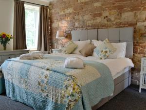 Plumbland的住宿－Holmegarth，一间卧室设有一张带砖墙的大床