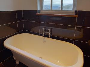 y baño con bañera y ventana. en Gowan Bank Farm Cottage, en Staveley