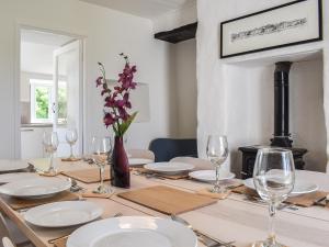 a dining room table with white plates and wine glasses at Pollards Cottage in Forrabury