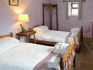 um quarto com 2 camas e uma mesa com um candeeiro em Newhouse Farm Barn em Neenton