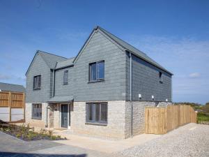 a house with a gray roof and a wooden fence at Fox Lodge in Crantock