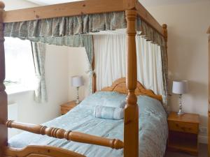 - une chambre avec un lit à baldaquin en bois et des draps bleus dans l'établissement Cherrytree Cottage, à Loftus