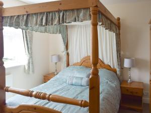 a bedroom with a wooden canopy bed with blue sheets at Cherrytree Cottage in Loftus