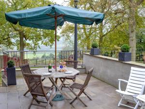 - une table et des chaises avec un parasol sur la terrasse dans l'établissement Coombe Wood Coach House, à Hawkinge