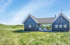 una casa azul en una colina con dos sillas en Nice Home In Thisted With Kitchen, en Klitmøller