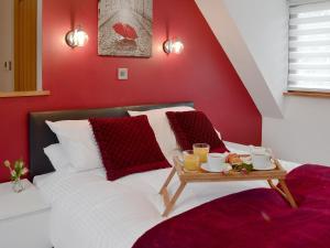 a red bedroom with a bed with a tray of food on it at Coombe Wood Coach House in Hawkinge