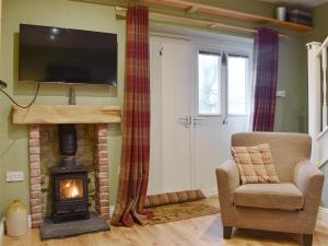 a living room with a wood stove and a chair at Sycamore Cottage in Consett