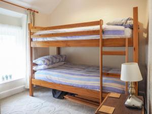 two bunk beds in a room with a lamp and a table at Meredith Cottage in Dolwyddelan